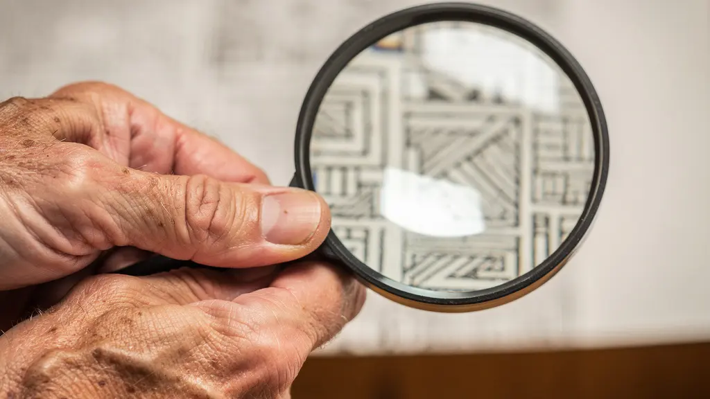 Vue macro de mains analysant minutieusement des documents avec une loupe