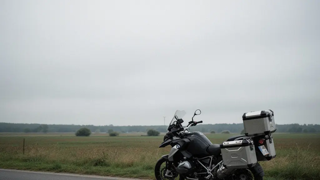 Moto de route équipée de valises latérales vue de trois quarts arrière sur une route dégagée, illustrant la prise au vent des bagages