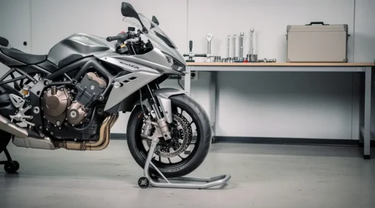 Moto en vente dans un atelier propre, moteur récemment révisé, outils mécaniques discrets et espace vide pour un titre.